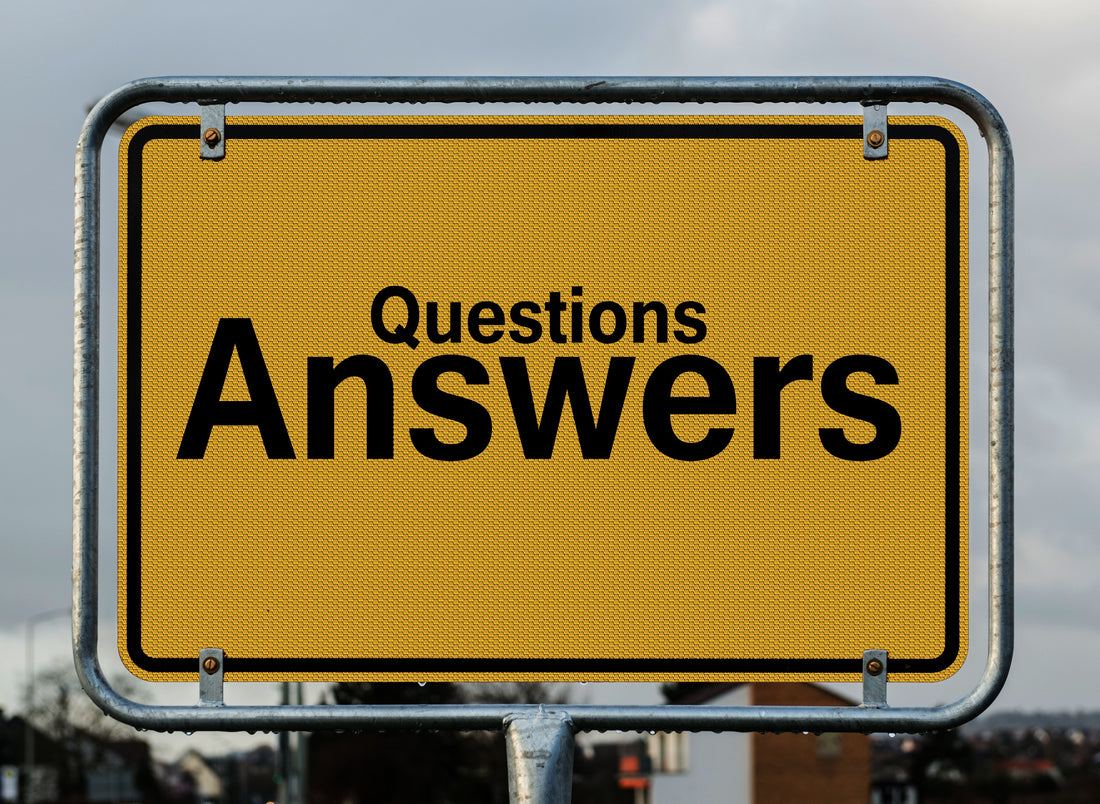 A photo of a bright yellow sign that says "Questions" in a medium font. Directly below "Questions" the word "Answers" is written in much larger letters.