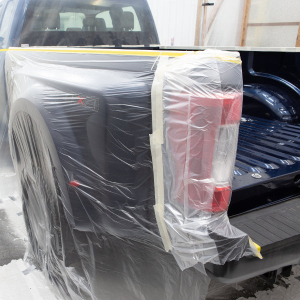 The back left taillight of a truck covered in the transparent pre-taped masking film for protection from paint.